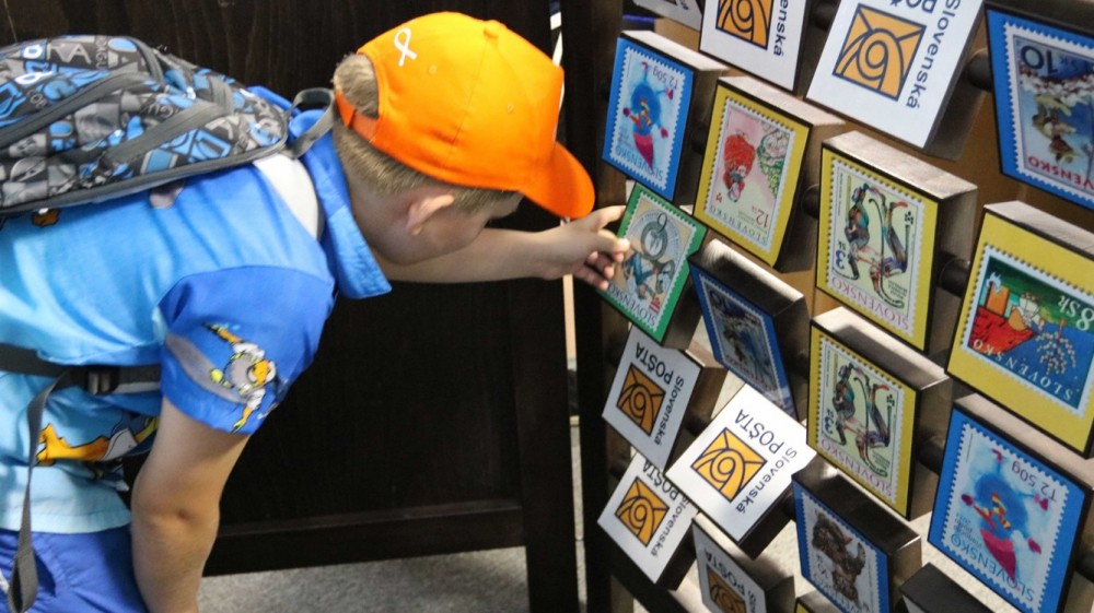Chlapec pozerajúci na známky v Poštovom múzeu v Banskej Bystrici