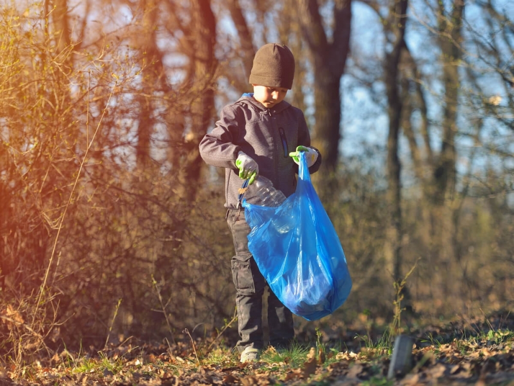 Chlapec zbiera odpadky v lese.